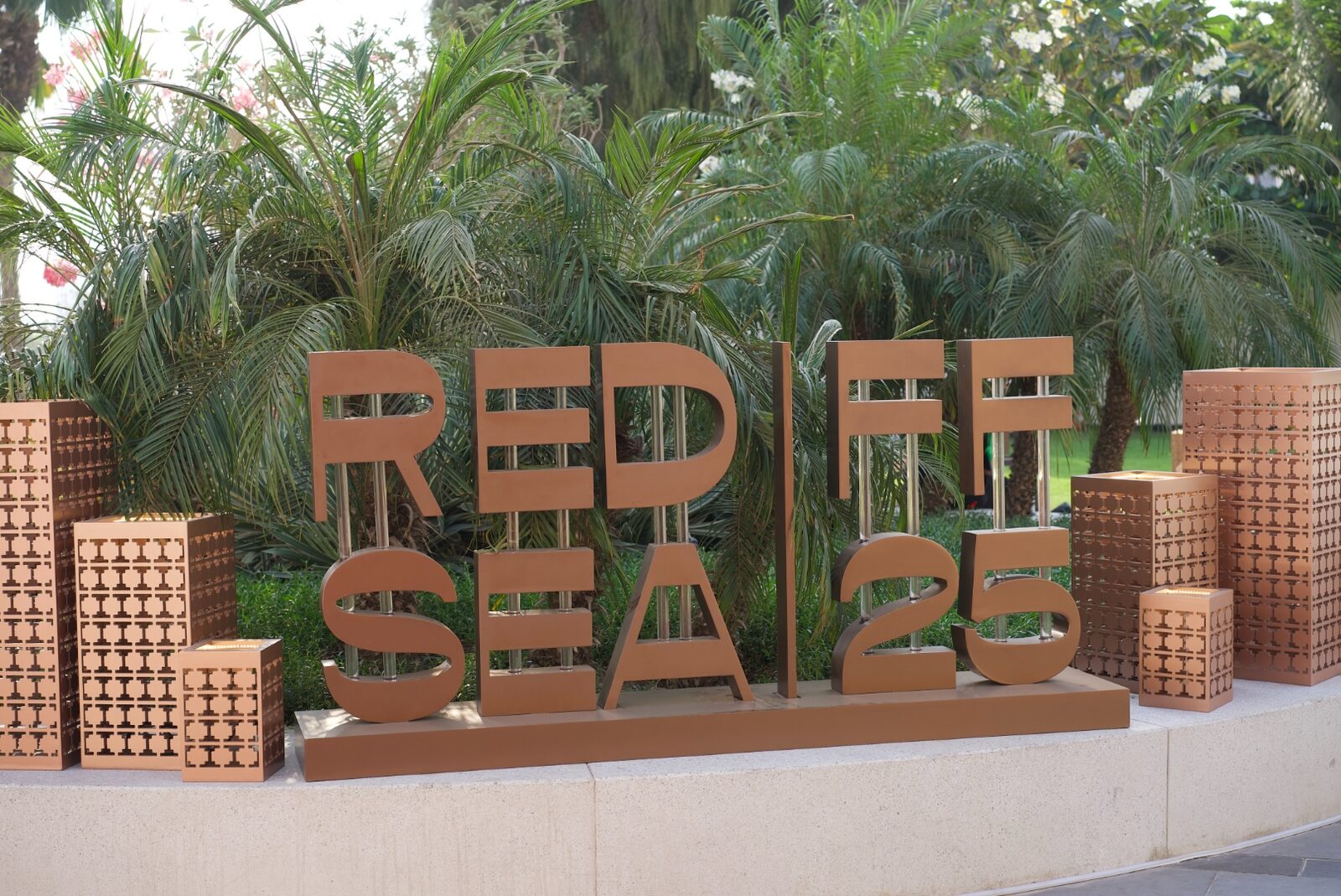 Sculptural RED SEA IFF 25 letters in an outdoor festival garden.